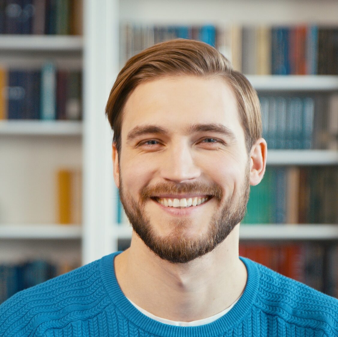 Young man smiles on the background of shelves